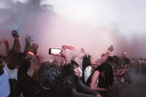Vibrant music festival scene with an excited crowd amidst colorful smoke, capturing the energy and joy.
